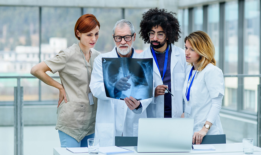 group-of-doctors-looking-at-x-ray-on-medical-confe-M4TET8S